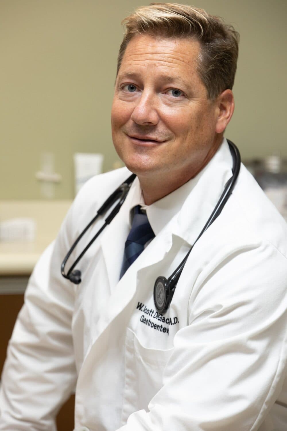 Dr. W. Scott DiGiacomo in a white coat with a stethoscope.